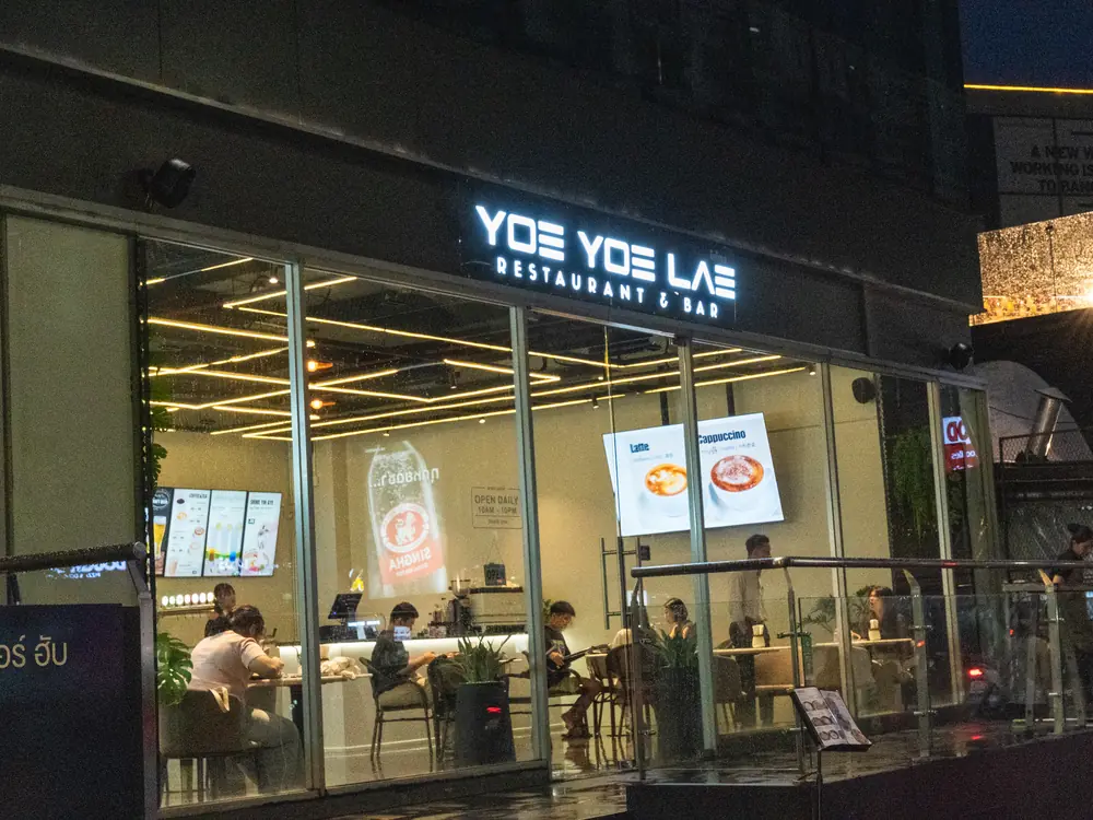 Yoe Yoe Lae Phra Khanong in the evening, its glass frontage lit from inside.