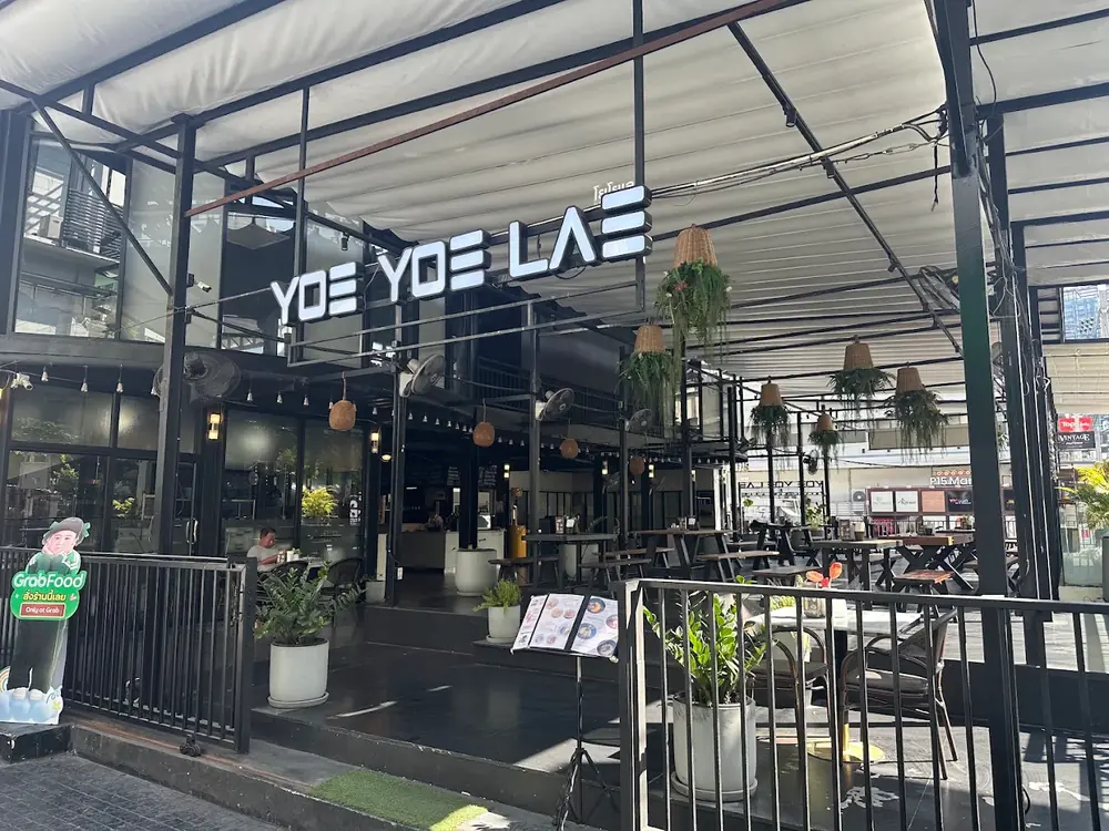 Yoe Yoe Lae Pratunam by day: the sign over an open terrace with hanging plants.