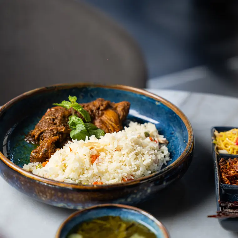 Curry and rice in a blue glazed bowl, with pickles alongside.