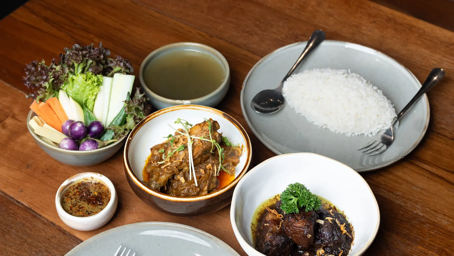 A Burmese table at Yoe Yoe Lae: pork curry, braised pork belly, steamed rice, clear soup, raw vegetables with balachaung.